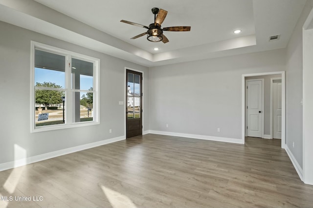 spare room featuring a tray ceiling, visible vents, and a healthy amount of sunlight