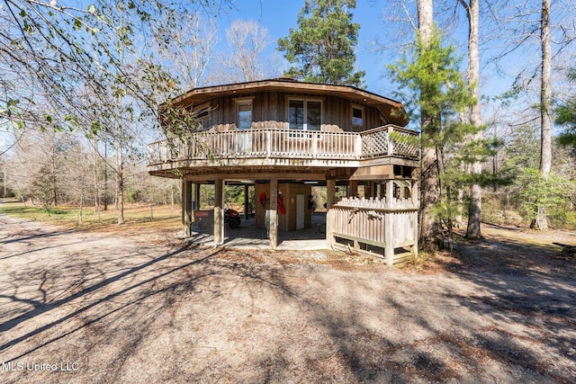 view of front of property featuring a carport, board and batten siding, a wooden deck, and driveway