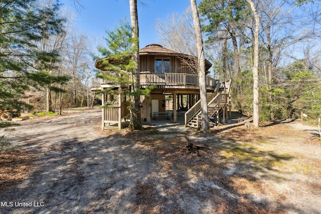 rear view of property with stairs, a carport, a wooden deck, and driveway