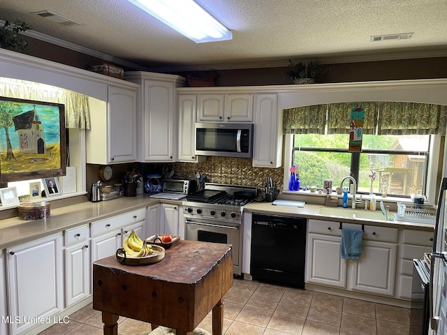 kitchen with white cabinets, light tile patterned floors, a textured ceiling, sink, and stainless steel appliances