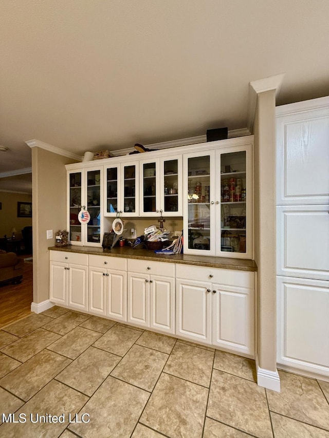 bar with light tile patterned floors, white cabinetry, and ornamental molding