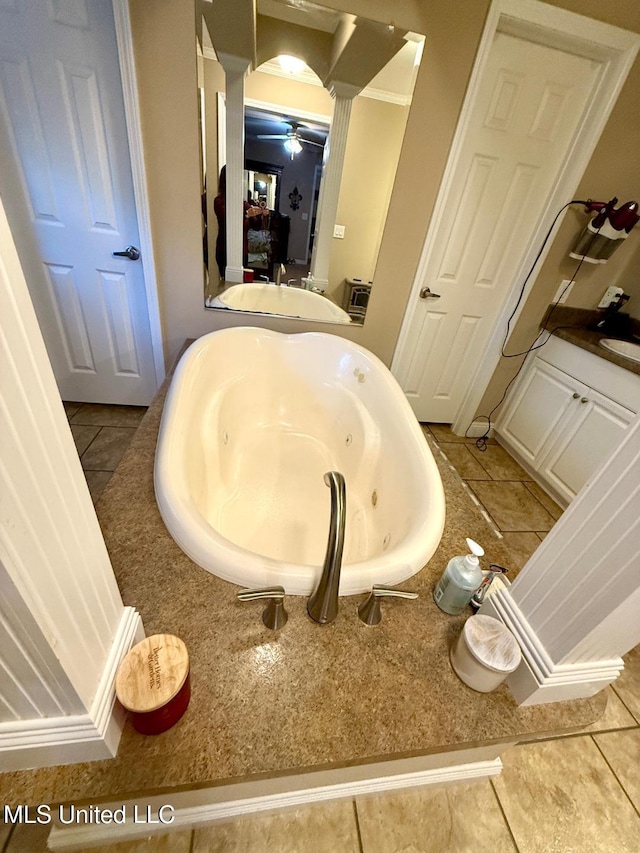 bathroom with tile patterned flooring, decorative columns, ceiling fan, and a tub