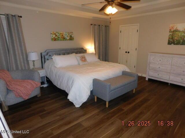 bedroom with dark wood-type flooring, ceiling fan, ornamental molding, and a closet