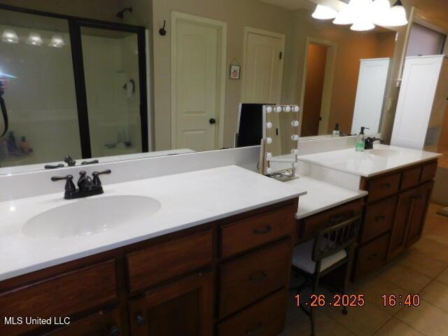 bathroom with a notable chandelier, vanity, tile patterned floors, and walk in shower