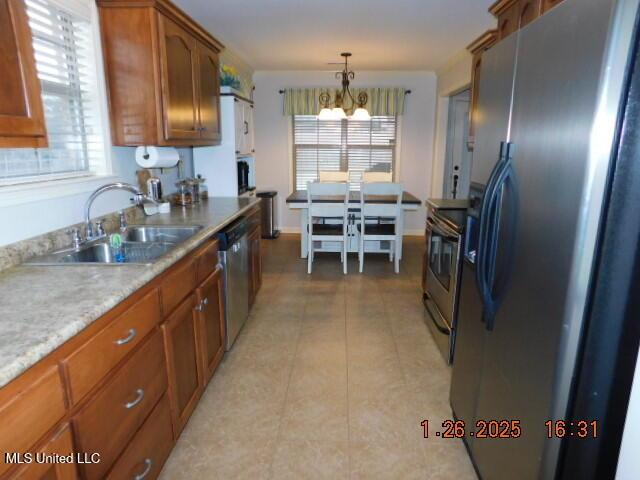 kitchen with an inviting chandelier, stainless steel appliances, sink, and hanging light fixtures