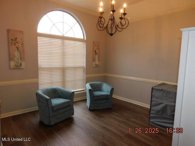 living area featuring ornamental molding, an inviting chandelier, and dark hardwood / wood-style flooring