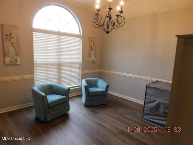 sitting room with crown molding, dark wood-type flooring, and a notable chandelier