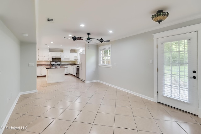 kitchen with appliances with stainless steel finishes, white cabinetry, ceiling fan, and light tile patterned floors