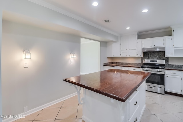 kitchen featuring tasteful backsplash, light tile patterned flooring, a center island, stainless steel range, and white cabinets