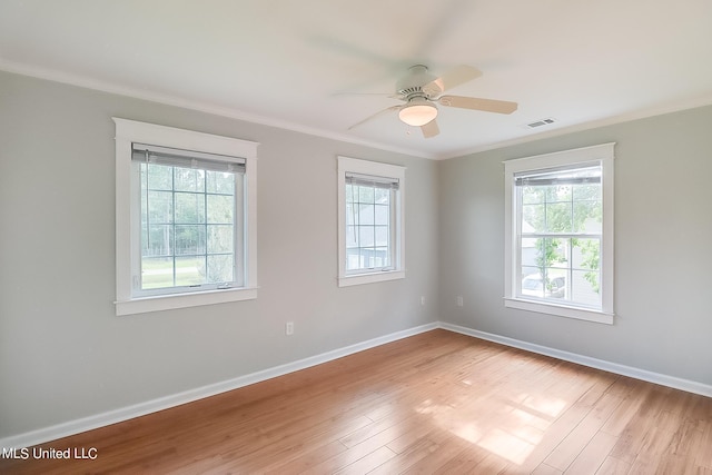 spare room with light hardwood / wood-style floors, ornamental molding, a wealth of natural light, and ceiling fan