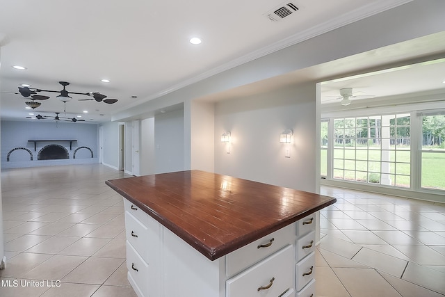 kitchen featuring butcher block counters, a center island, a brick fireplace, and white cabinets