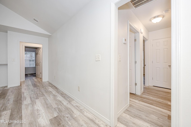 hallway featuring vaulted ceiling and light hardwood / wood-style flooring