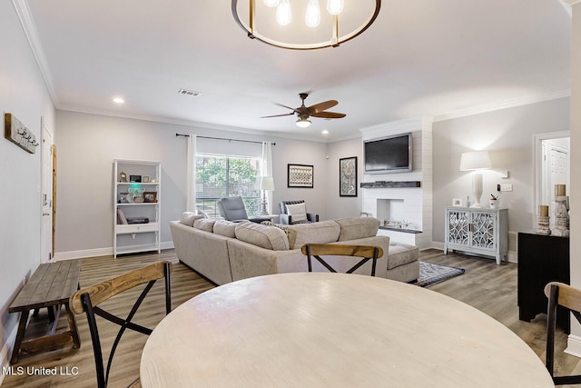 118 Armand Oaks, Ocean Springs, MS 39564 - dining room with crown molding, a ceiling fan, a large fireplace, wood finished floors, and baseboards