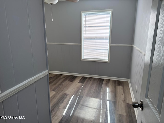 unfurnished room featuring wooden walls and dark wood-type flooring