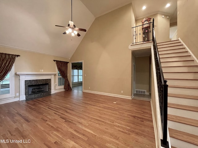 unfurnished living room with high vaulted ceiling, hardwood / wood-style flooring, ornamental molding, and ceiling fan