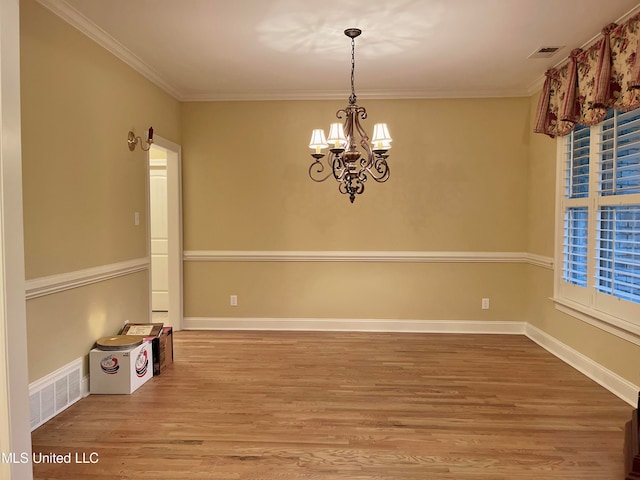 empty room featuring crown molding, hardwood / wood-style flooring, and an inviting chandelier