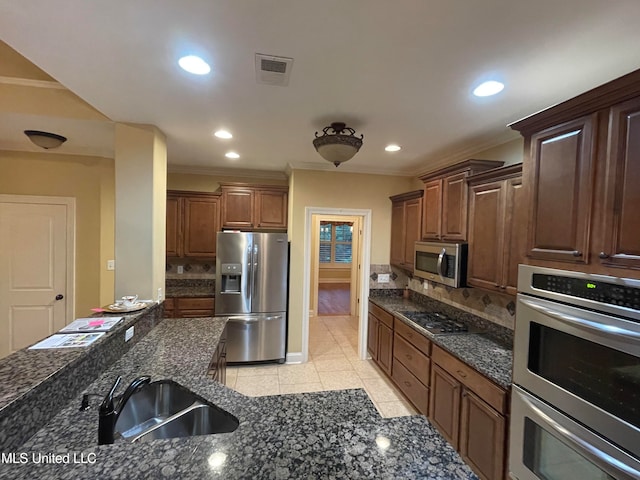 kitchen with tasteful backsplash, appliances with stainless steel finishes, sink, ornamental molding, and light tile patterned floors