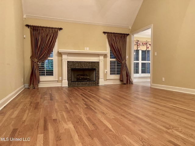 unfurnished living room with vaulted ceiling, crown molding, and light hardwood / wood-style flooring