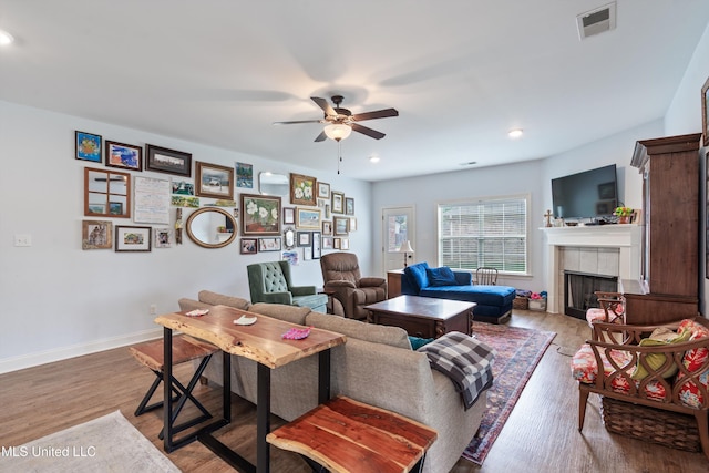 living area with a ceiling fan, wood finished floors, a fireplace, recessed lighting, and baseboards