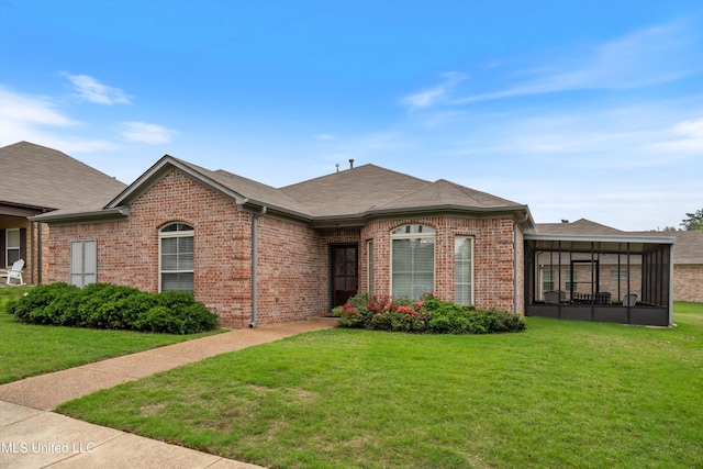 view of front of house with brick siding, a sunroom, and a front yard