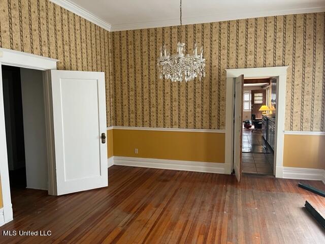 unfurnished dining area with crown molding, dark hardwood / wood-style floors, and a notable chandelier