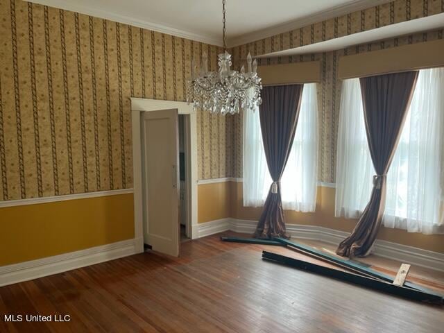 unfurnished room featuring a notable chandelier, ornamental molding, and hardwood / wood-style floors