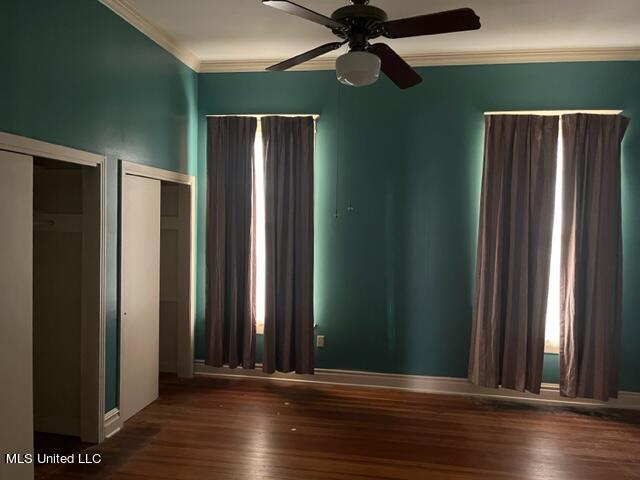 empty room with ornamental molding, ceiling fan, and dark hardwood / wood-style flooring