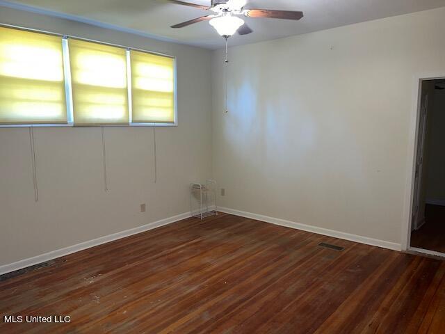 empty room featuring dark wood-type flooring and ceiling fan