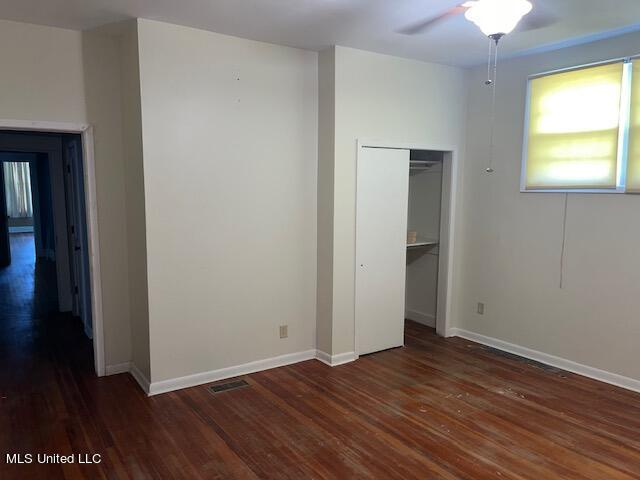 unfurnished bedroom with ceiling fan, a closet, and dark hardwood / wood-style flooring