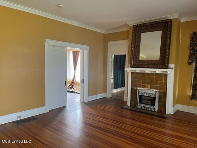 unfurnished living room featuring ornamental molding, a tiled fireplace, and dark hardwood / wood-style floors