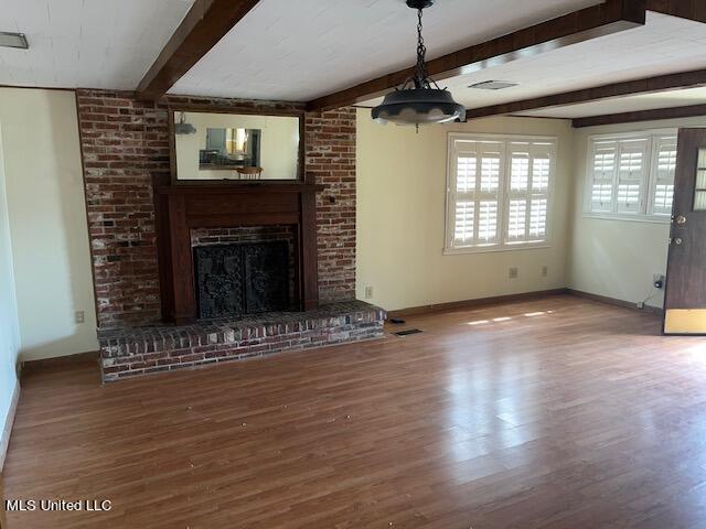 unfurnished living room with beam ceiling, wood-type flooring, and a brick fireplace