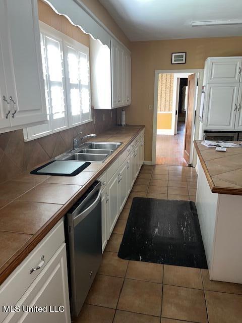 kitchen featuring tile counters, dishwasher, white cabinets, and tasteful backsplash