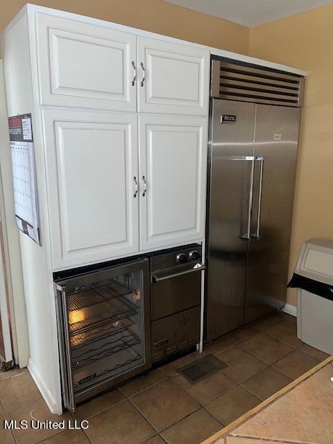 kitchen featuring dark tile patterned floors, white cabinets, and stainless steel built in refrigerator