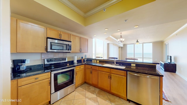 kitchen with sink, appliances with stainless steel finishes, crown molding, and dark stone countertops