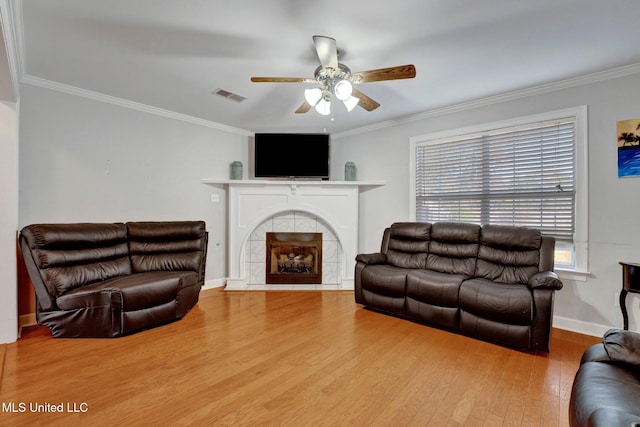 living room featuring a fireplace, hardwood / wood-style flooring, ceiling fan, and crown molding