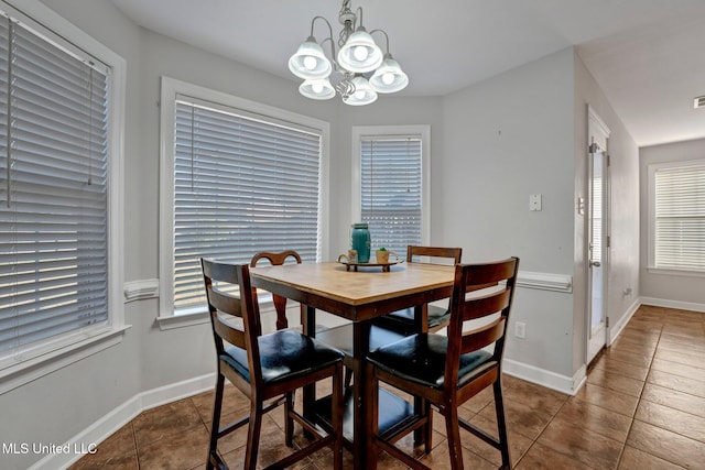 dining room featuring a healthy amount of sunlight, dark tile patterned floors, and a chandelier