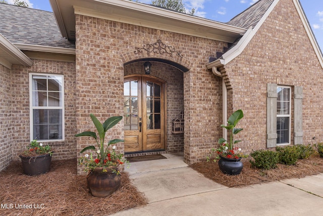 doorway to property with brick siding, roof with shingles, and french doors