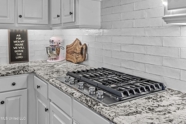 kitchen featuring stainless steel gas cooktop, light stone counters, decorative backsplash, and white cabinets