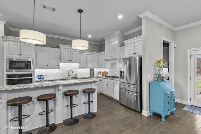 kitchen featuring crown molding, visible vents, appliances with stainless steel finishes, white cabinetry, and a kitchen breakfast bar