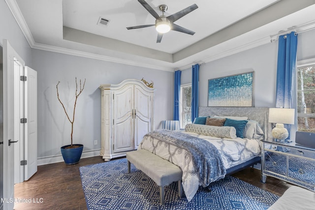 bedroom featuring baseboards, visible vents, a raised ceiling, ornamental molding, and wood finished floors