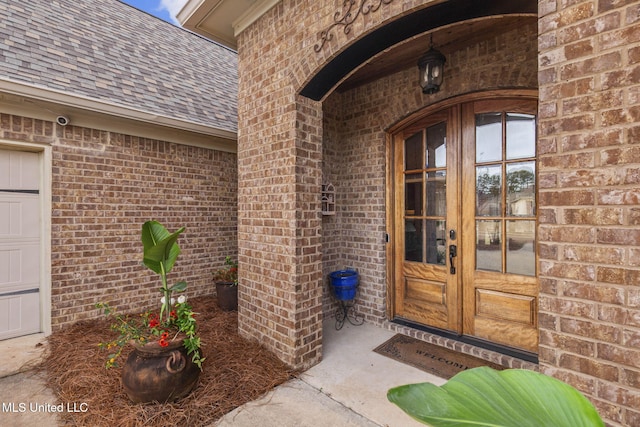 entrance to property with french doors, brick siding, and a shingled roof