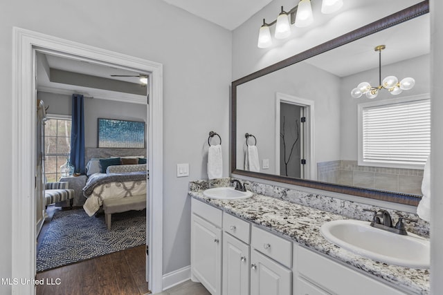 full bath featuring double vanity, connected bathroom, a sink, and wood finished floors