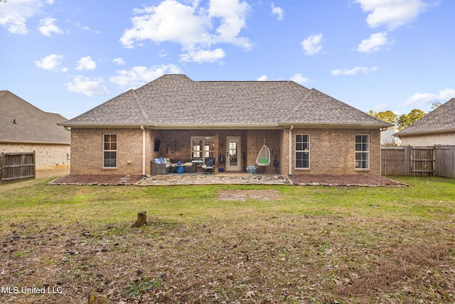 rear view of house featuring a shingled roof, a patio, a lawn, and a fenced backyard