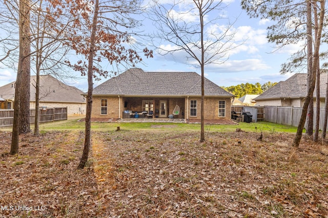 rear view of house featuring a fenced backyard, brick siding, a yard, roof with shingles, and a patio area