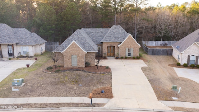 view of front of house with french doors, brick siding, a shingled roof, and fence