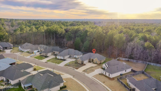 aerial view at dusk featuring a residential view and a wooded view