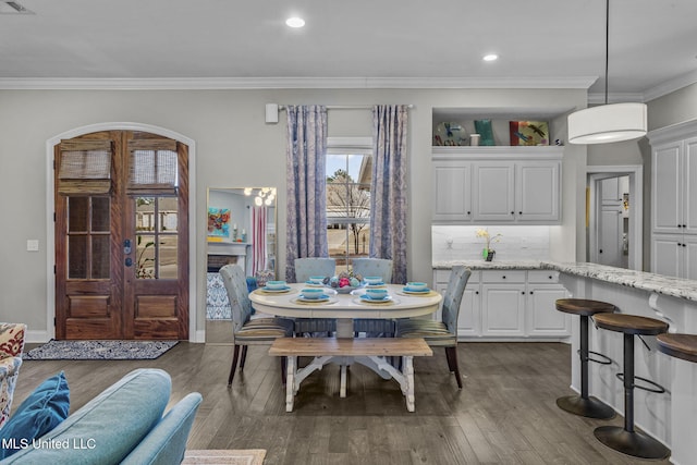 dining area featuring baseboards, arched walkways, ornamental molding, dark wood-type flooring, and recessed lighting