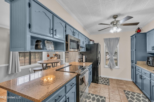 kitchen featuring ceiling fan, light tile patterned floors, appliances with stainless steel finishes, and blue cabinetry