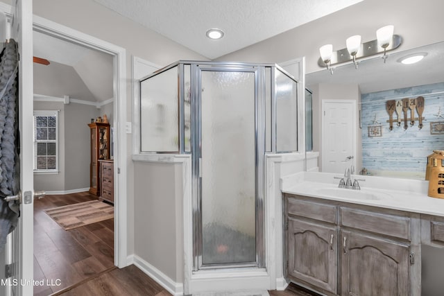 bathroom with wood-type flooring, walk in shower, vanity, and vaulted ceiling