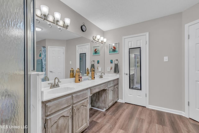 bathroom with vanity, a shower with shower curtain, a textured ceiling, and hardwood / wood-style flooring